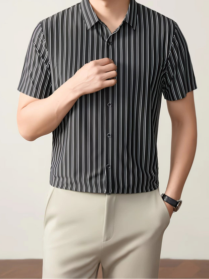 GKSEN black and white striped men’s shirt shown in a front model pose with the hand near the collar, short sleeves, and button detail.