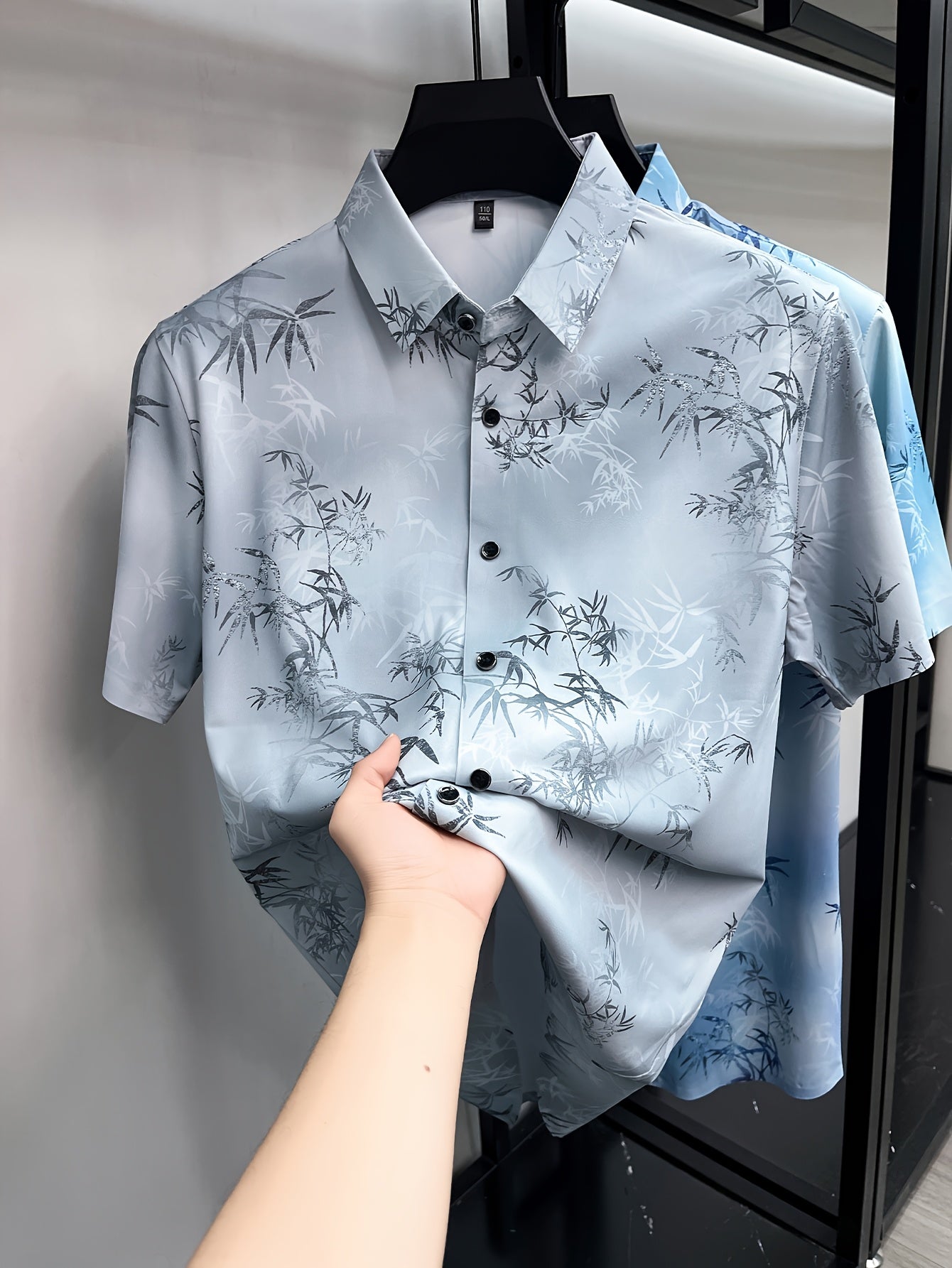 GKSEN light grey bamboo leaf print men’s shirt shown in a front hanger view with short sleeves, collar, buttons, and all-over print.