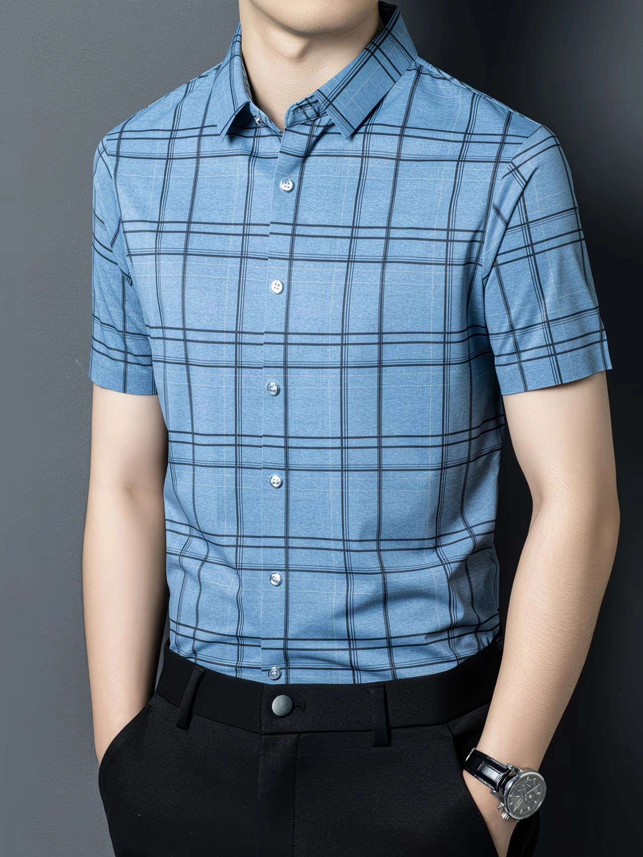 GKSEN sky blue grid check men’s shirt shown in a three-quarter front model pose with short sleeves and black trousers.