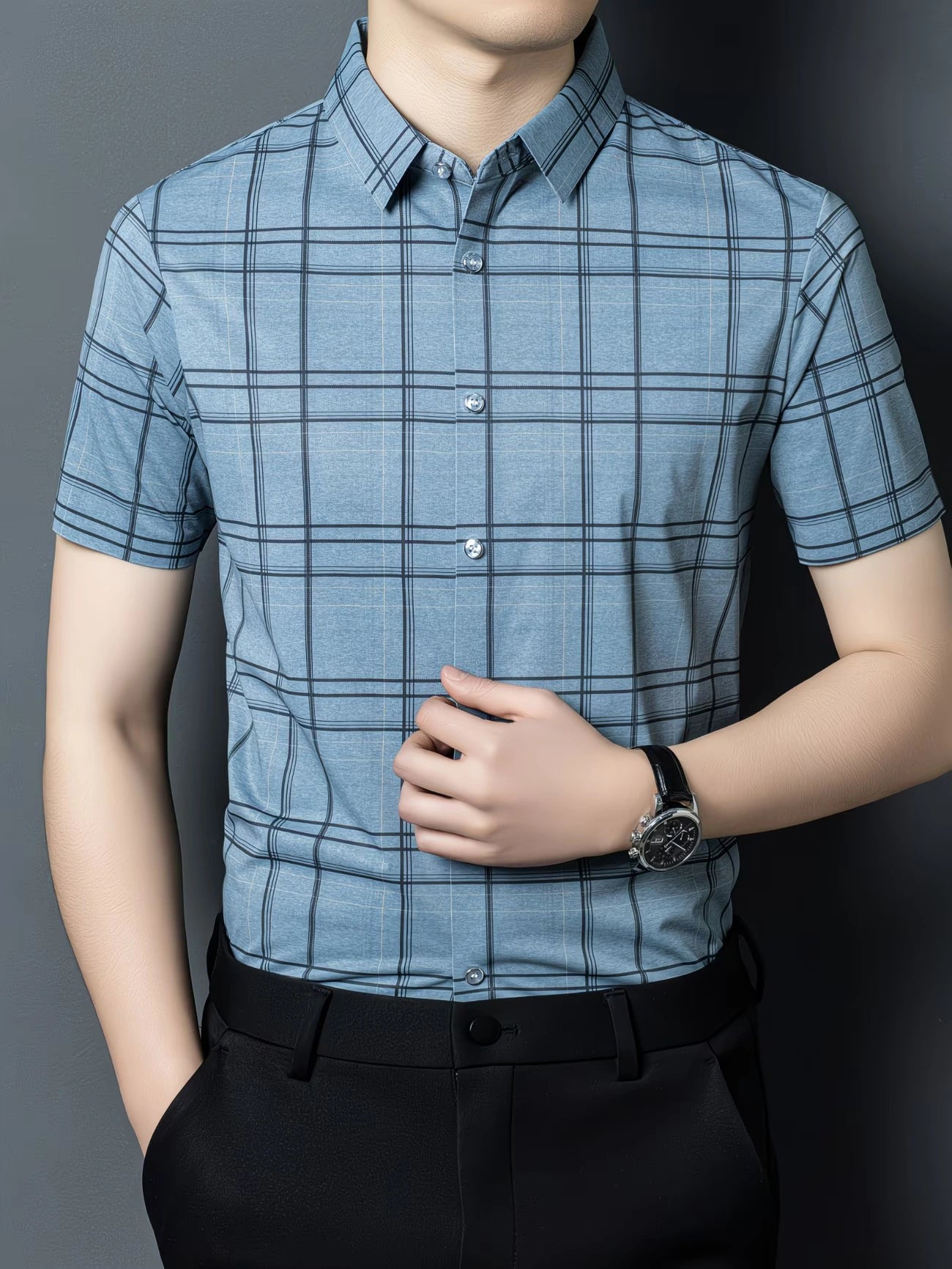 GKSEN slate blue windowpane check men’s shirt shown from the front with the model adjusting the shirt and short sleeve styling visible.