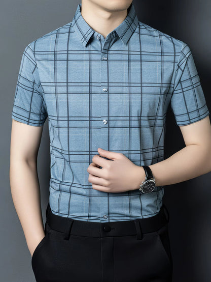 GKSEN slate blue windowpane check men’s shirt shown from the front with the model adjusting the shirt and short sleeve styling visible.