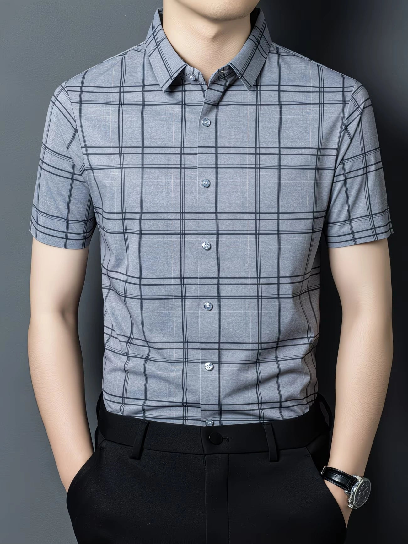GKSEN men’s shirt in steel grey windowpane checks shown in a front model pose with short sleeves, collar, and light button detail.