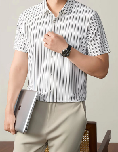 GKSEN white black pinstripe men’s shirt shown in a front model pose with short sleeves, light trousers, and laptop styling.