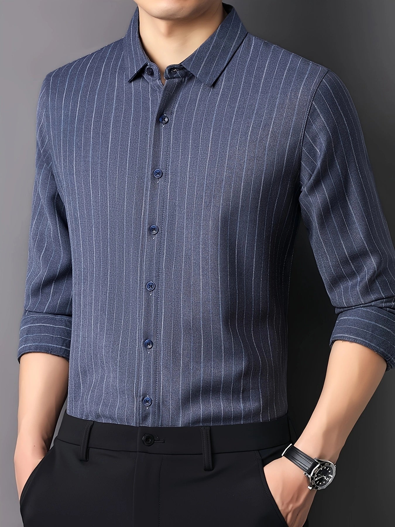 Angled front view of GKSEN steel blue vertical stripe men’s shirt styled with black trousers and rolled sleeves.